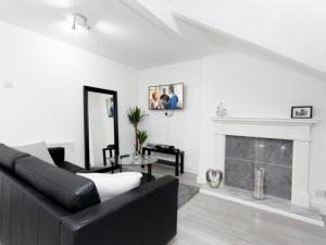 a living room with a black couch and a fireplace at Live in Leeds Grange Apartments in Leeds