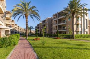 a brick walkway in front of a building with palm trees at مارينا دلتا in ‘Izbat Abū Sulayman