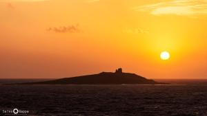 a castle on an island in the ocean at sunset at La Casetta sul Mare in Isola delle Femmine