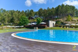 a pool at a resort with tables and umbrellas at DiverLanhoso - Alojamento in Póvoa de Lanhoso