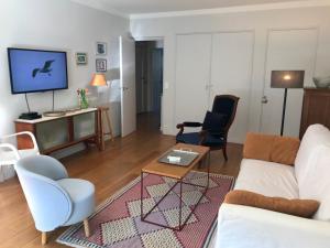 a living room with a couch and chairs and a tv at Standing-Montparnasse in Paris