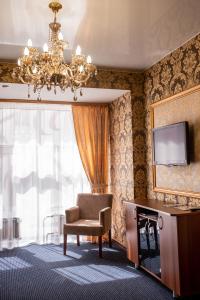 Habitación con silla, TV y lámpara de araña. en Malibu Hotel, en Omsk