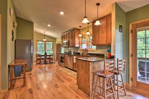 a kitchen with wooden cabinets and a kitchen island with bar stools at Charming Galax Retreat with Wraparound Deck! in Galax