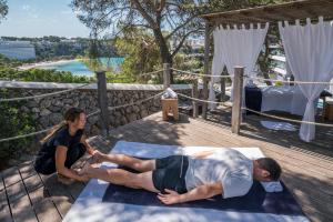 a man and a woman doing yoga on a deck at ARTIEM Audax - Adults Only in Cala Galdana