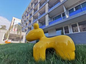una estatua de perro amarillo en el césped frente a un edificio en Spring Holiday Resort en Neptun