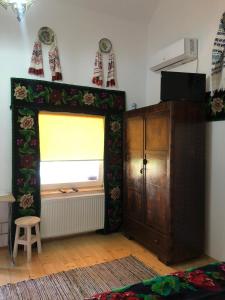 ein Wohnzimmer mit einem Fenster und einem Holzschrank in der Unterkunft Casa Cezara in Silvaşu de Jos