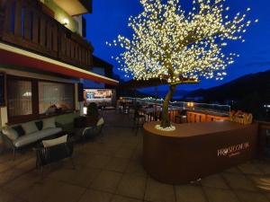 a tree with lights on a patio at night at B&B La Montanara in San Martino di Castrozza