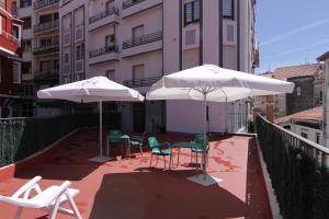 three chairs and two umbrellas on a balcony at Xixili in Bermeo