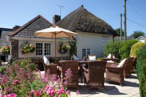 a patio with a table and chairs and an umbrella at Yalbury Cottage in Dorchester