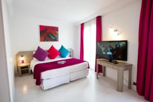 a bedroom with a bed with red curtains and a television at Cristal Hôtel & Spa in Cannes