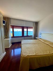 a bedroom with a bed and two windows at Camere Al Veliero in Gardone Riviera