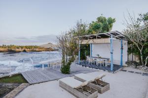 a pavilion with a table and chairs next to the water at Villa Waru in Nusa Lembongan