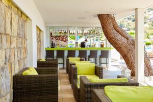 a bar with brown wicker chairs and a tree at Universal Hotel Laguna in Canyamel