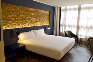 um quarto com uma cama branca e uma grande pintura na parede em Hotel Alda Galería Coruña na Corunha