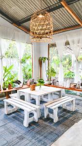 a dining room with a white table and benches at Beanbag Bintan Backpacker in Kangkakawal