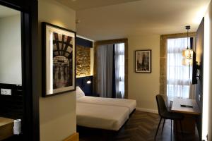 Hotel Alda Galería Coruña في لا كورونيا: غرفة في الفندق بها سرير ومكتب ونافذة