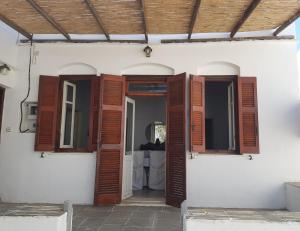 an open door of a white house with wooden shutters at Artemonahi Traditional Cosy House in Artemonas