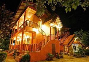 a large house with a staircase in front of it at night at Ban Tonnam Resort in Suan Phung