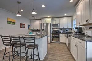 a kitchen with white cabinets and a island with bar stools at Gulfport Bungalow by Jones ParkandBeach Access! in Gulfport