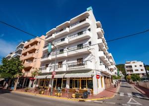 een hoog wit gebouw op een straathoek met een gebouw bij Hostal Santa Eulalia in Santa Eularia des Riu