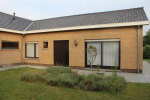 uma casa de tijolos com uma porta preta e janelas em Huis Ter Duin em Koksijde