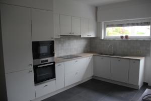 een keuken met witte kasten, een wastafel en een magnetron bij Huis Ter Duin in Koksijde