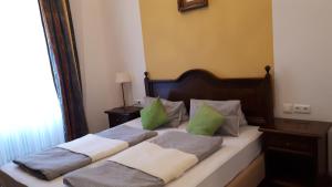 Una cama con almohadas verdes y blancas. en Gasthof-Pension Schwarzer Bär, en Waidhofen an der Ybbs