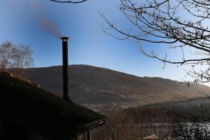 a mountain in the distance with a smoke stack at Cosy Modern Nordic Lodge w/ Loch View & Log Burner in Lochearnhead