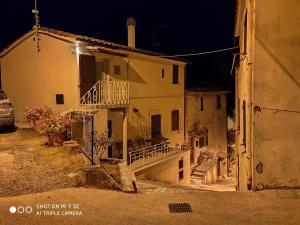 an old house with stairs in a street at night at Bagni San Filippo Casa gelsomino in Bagni San Filippo