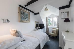 a white bedroom with a bed and a desk at The Mount Pleasant Hotel in Sidmouth