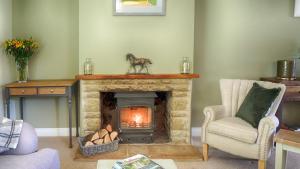 a living room with a fireplace with a horse statue on top at Ivy Cottage in Bourton on the Water