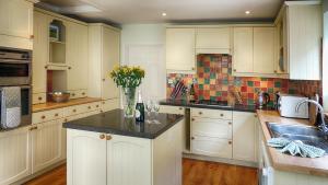 uma cozinha com armários brancos e um vaso de flores em Ivy Cottage em Bourton on the Water