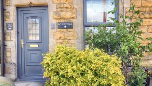 una porta blu di una casa con un cespuglio di fronte di Ivy Cottage a Bourton on the Water Altre 20 foto