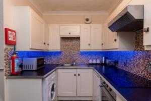 a kitchen with white cabinets and blue tiles on the wall at Cattle Market View Apartment in Boston
