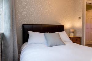 a bed with a black headboard and white pillows at Cattle Market View Apartment in Boston