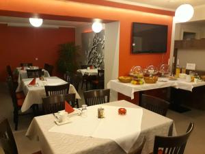 ein Restaurant mit weißen Tischen und Stühlen sowie einem Flachbild-TV in der Unterkunft Culina in Oberlungwitz