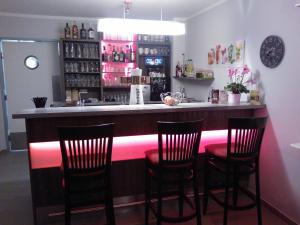 eine Bar mit 4 Stühlen und einer Theke mit rosafarbener Beleuchtung in der Unterkunft Culina in Oberlungwitz