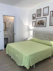 um quarto com uma grande cama verde e quadros na parede em Estatesalento em Leuca