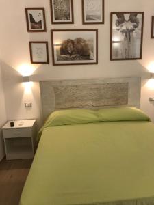 1 dormitorio con cama verde y cuadros en la pared en Estatesalento, en Leuca