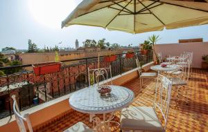 einen Balkon mit Tischen, Stühlen und einem Sonnenschirm in der Unterkunft Riad Dar Essalam in Marrakesch