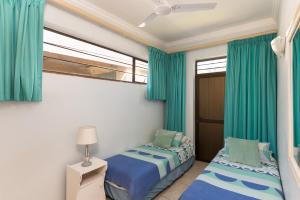 two beds in a room with blue curtains at Boulder Bay 1 in Ballito
