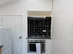 a kitchen with a stove and a black tile wall at Dean House in Leeds