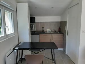 una piccola cucina con tavolo e sedie neri di Studio équipé indépendant chaleureux lumineux a Saubens