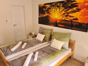 a bedroom with two beds and a painting on the wall at Napfény Apartman in Makó