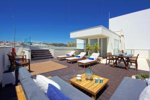 a patio with couches and tables on a roof at Casa da Bandeira -Perfect Location-Beach front- Rooftop Pool by DreamvillasAlbufeira in Albufeira