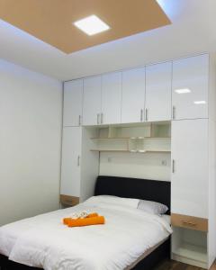 ein Schlafzimmer mit weißen Schränken und einem orangenen Handtuch auf dem Bett in der Unterkunft Apartmani Šarović in Tjentište