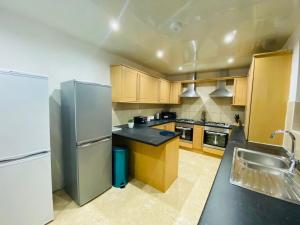 a kitchen with wooden cabinets and a stainless steel refrigerator at Callerton House in Newcastle upon Tyne