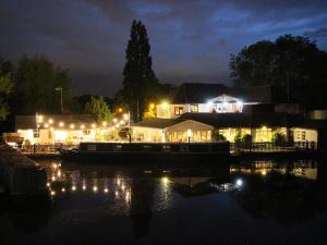 a boat in the water at night with lights at The WatersEdge, Canal Cottages in Hillingdon