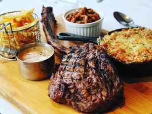 a wooden cutting board with a steak and other foods at The WatersEdge, Canal Cottages in Hillingdon +14 photos