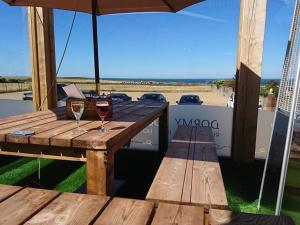 a wooden picnic table with two glasses of wine at The Dormy House Hotel in Cromer